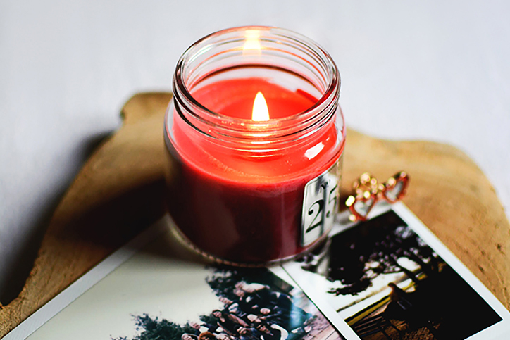 A red candle lit next to some photographs