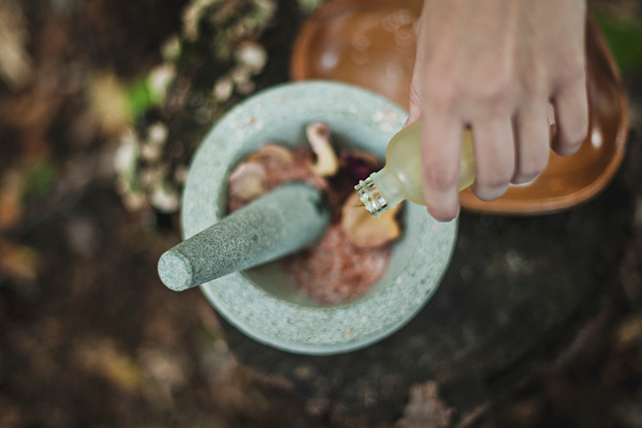 Someone pouring a vial into a mortar and pestle