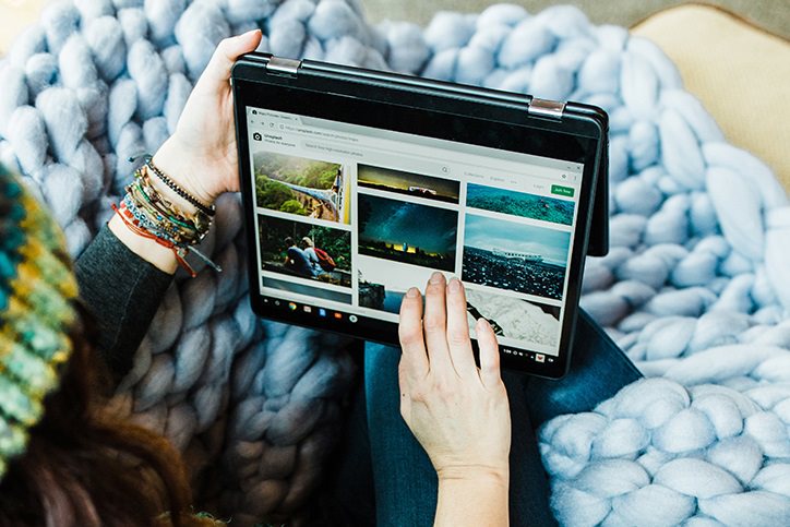 A woman in a blanket browsing photos on her tablet