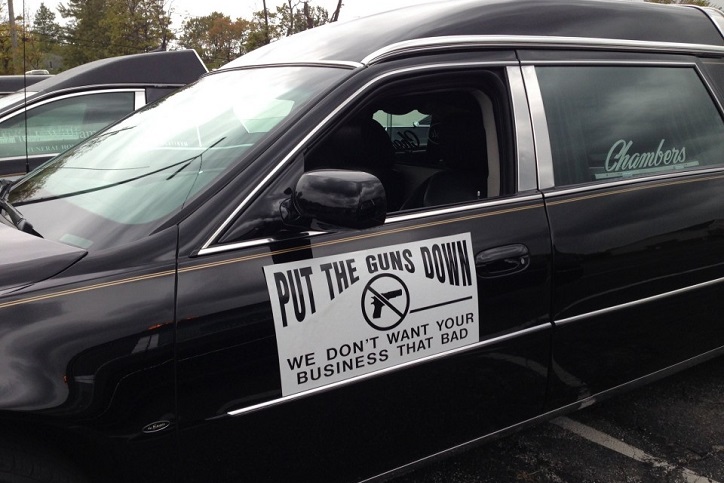 A sign in a hearse window reads put the guns down we don't want your business that bad