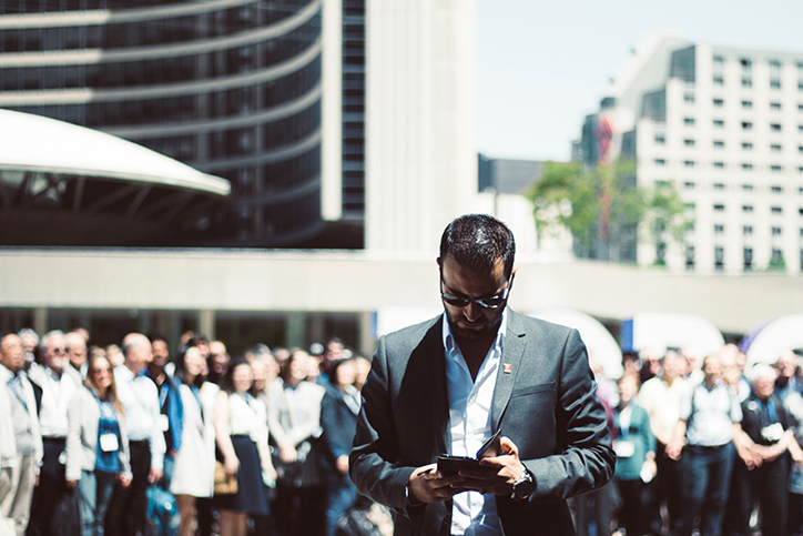 A man on his phone standing apart from a crowd