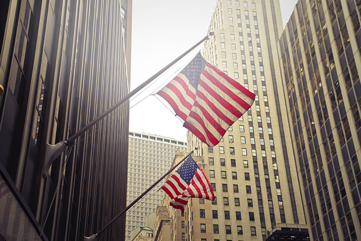 Two American flags on flagpoles on a building downtown