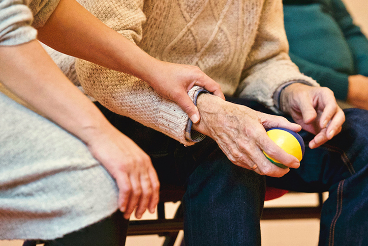 An older man holding a ball and working on physical therapy