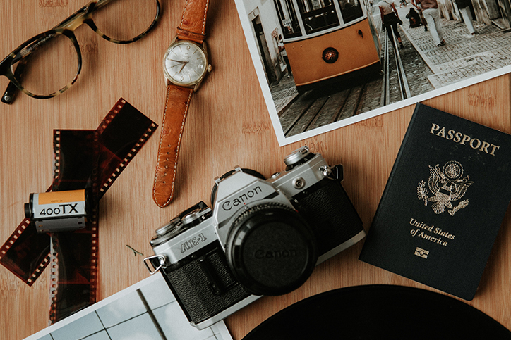 A Canon camera next to a passport and a watch