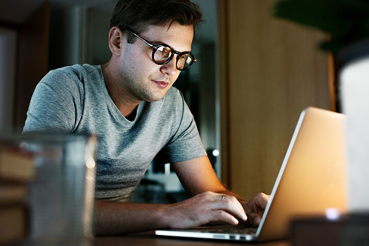 A man with glasses working on a laptop