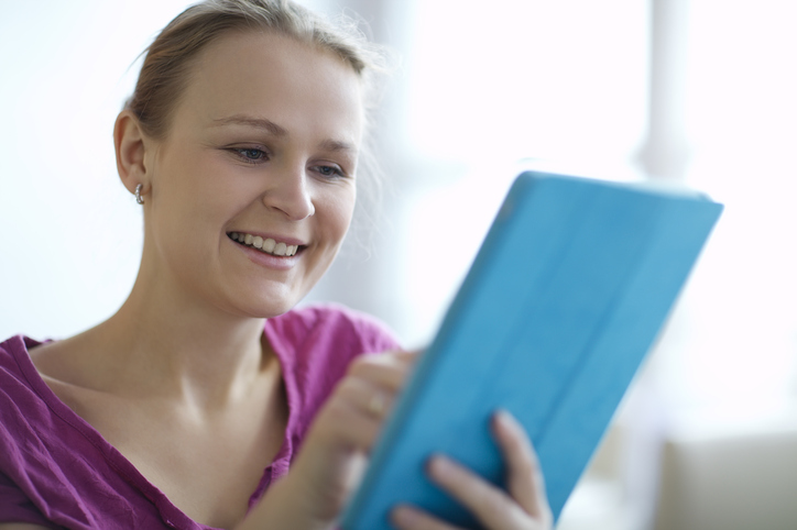 A woman smiling at a tablet