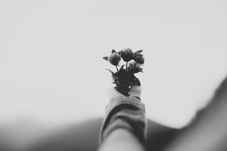 An outstretched hand holding flowers in black and white