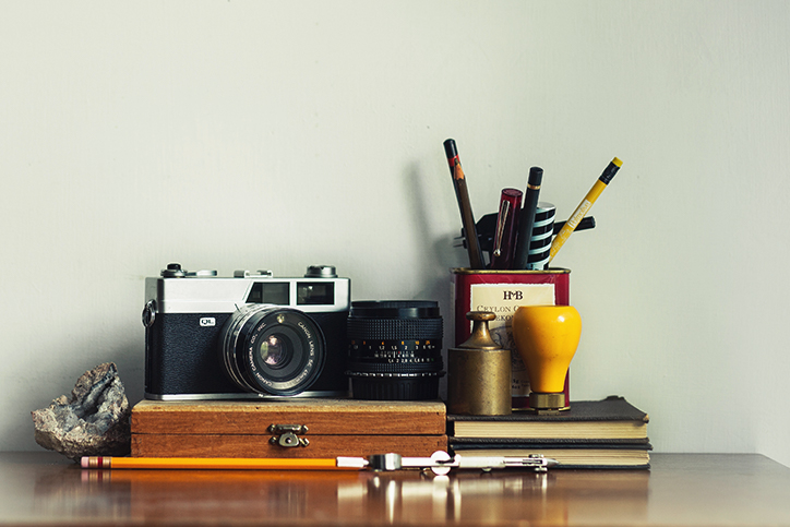 A shelf with books, pencils, and a camera