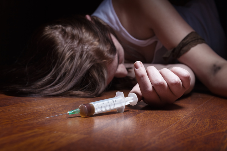 A victim of the opioid epidemic holds a needle of heroin