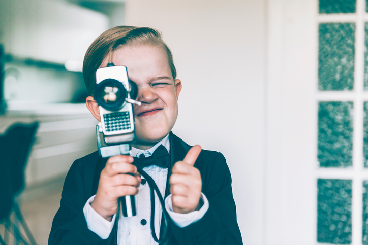 A kid holding a video camera holds a thumbs up