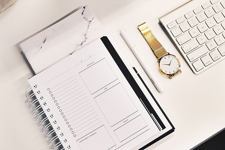A planner and a watch on a desk