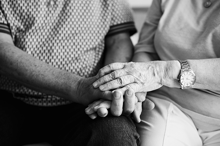 two elderly people holding hands