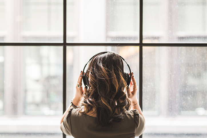 woman looking out a window and wearing headphones