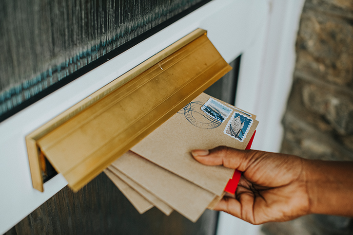 hands placing letters in mail slot