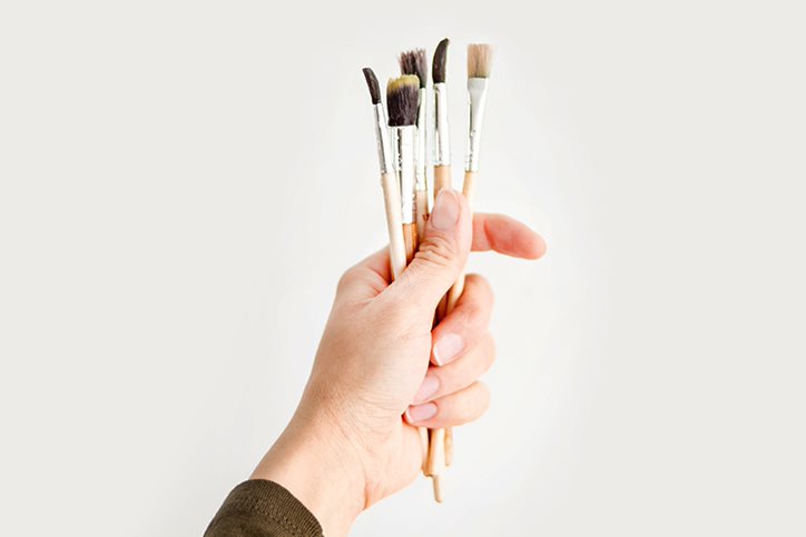 Hands holding paintbrushes