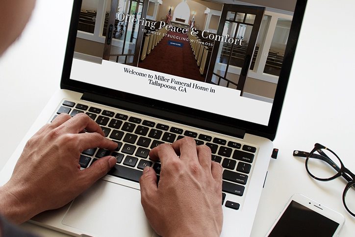 person looking at Miller Funeral Home website on a laptop