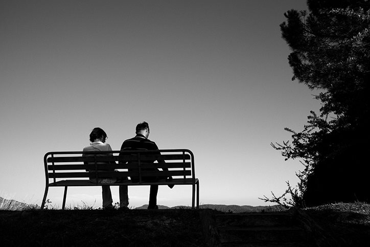 Two people sitting on a bench outside