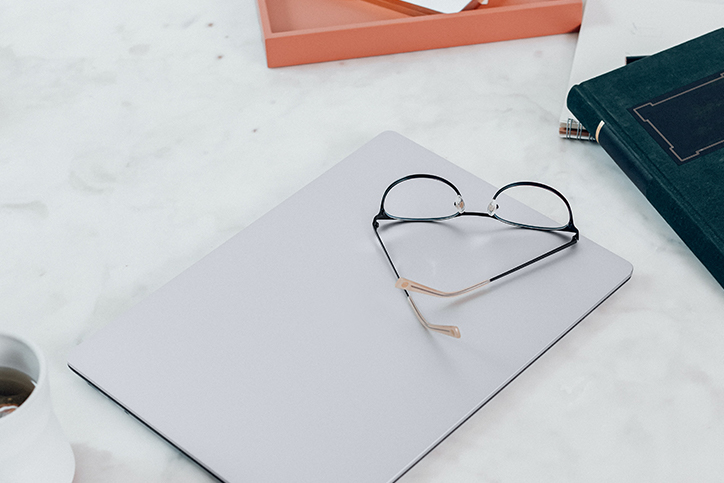 Laptop, coffee, notebook, and glasses on a marble desk