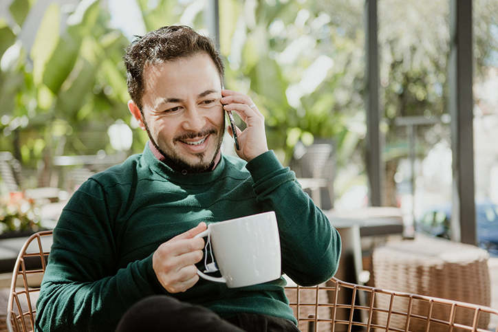 Man holding a cup of coffee and making a phone call
