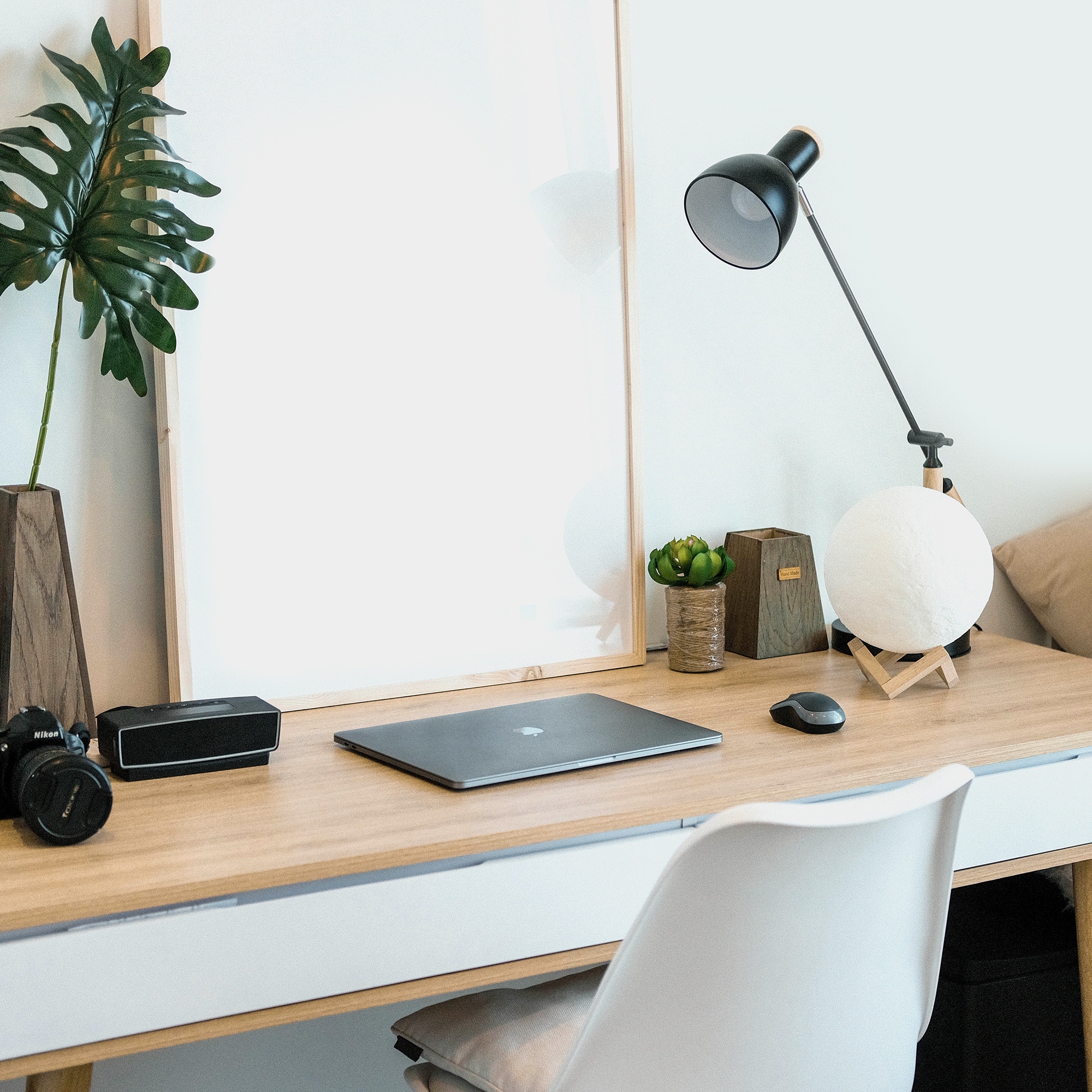 a desk with a laptop, lamp, and plant